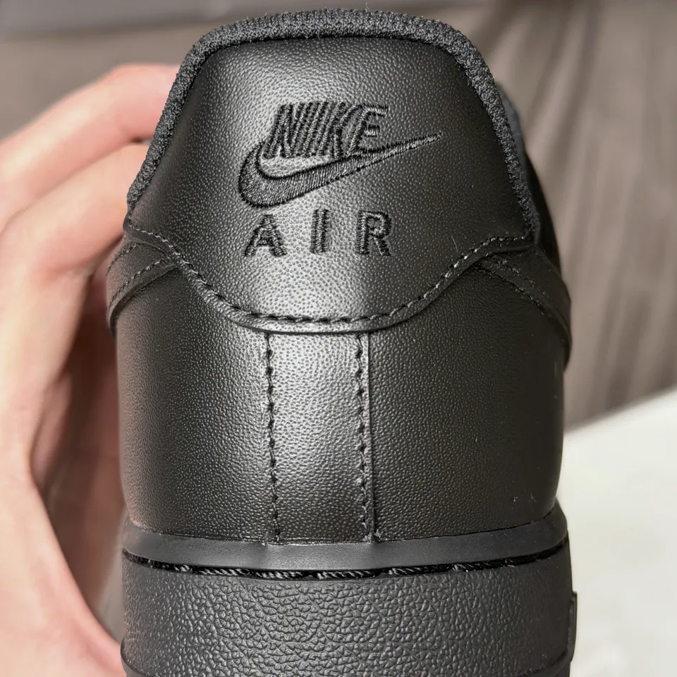 Задник чёрного кроссовка с вышитой маркировкой Nike Air, центральным швом и линией подошвы