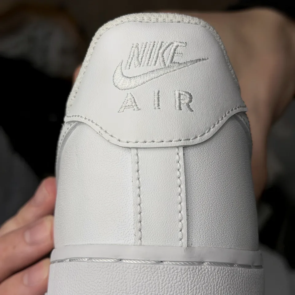 Задник белого кроссовка с вышитой маркировкой Nike Air, центральным швом и линией подошвы